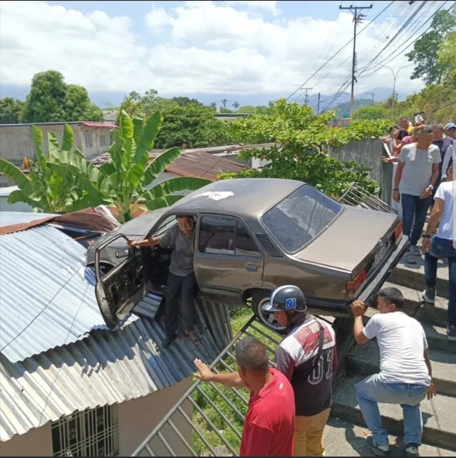 accidente Carro quedó sobre el techo de una vivienda
